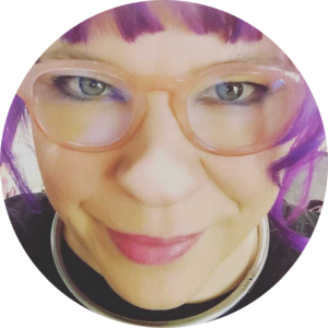 ducky's face with purple hair framing her bespectacled face