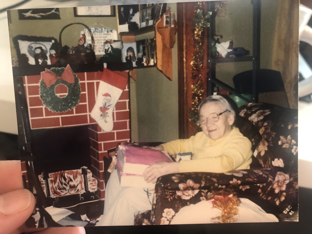 My little grandma sitting in a big chair with a mountain of Christmas gifts in her lap.